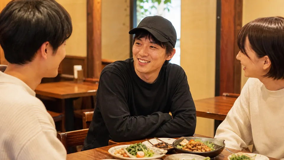 カジュアルな飲食店で帽子をかぶって友人と会話する男性