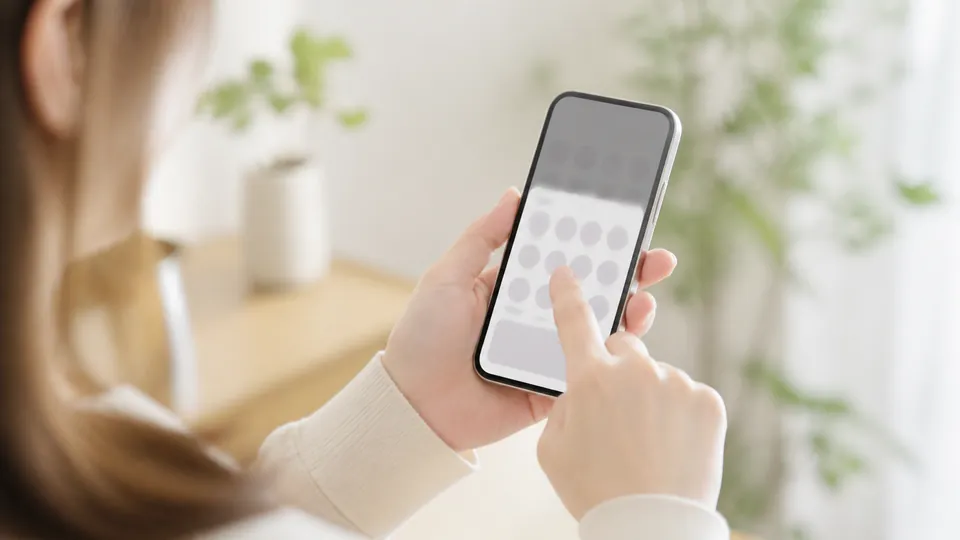 LINEの共有画面に表示される最近の相手をスマートフォンで確認する女性