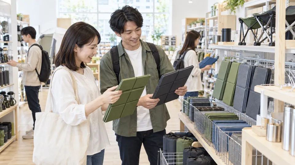 レジャー用品売り場で折りたたみマットを比べる買い物客